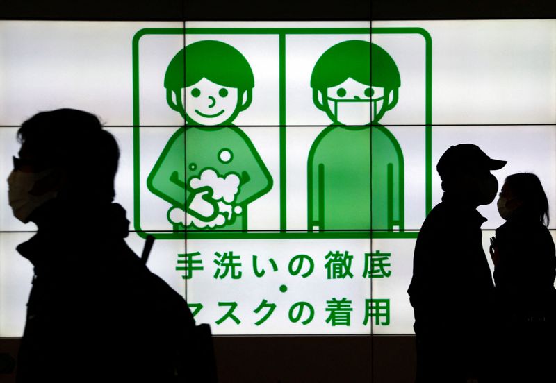 &copy; Reuters. Pessoas usando máscaras passam por painéis com informações sobre a Covid-19 em Tóquio
01/02/2022 REUTERS/Issei Kato