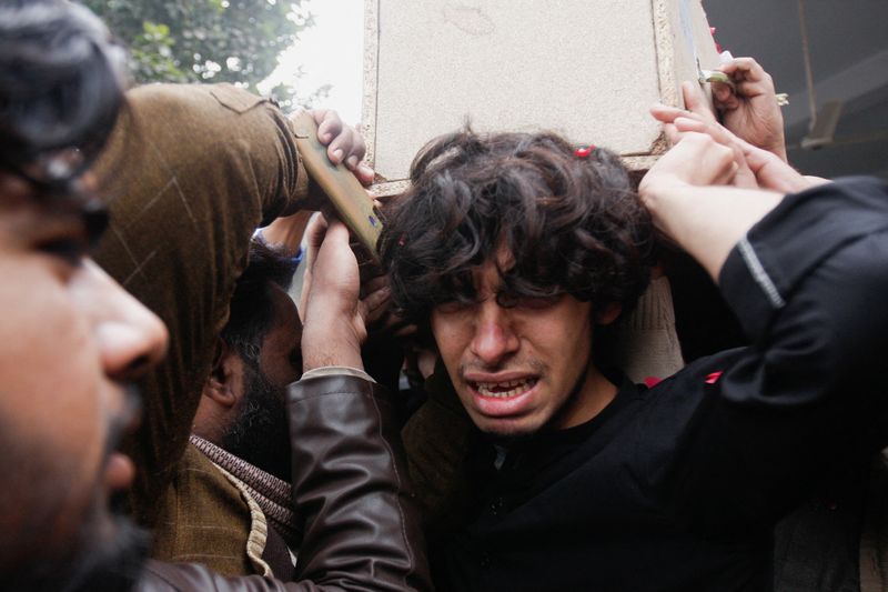 © Reuters. شقيق ضابط في الجيش، قُتل في هجوم على قاعدة عسكرية في ناوشكي، يبكي أثناء حمل نعش أخيه خلال جنازته في فيصل آباد بباكستان يوم الجمعة. تصوير:رويترز.
