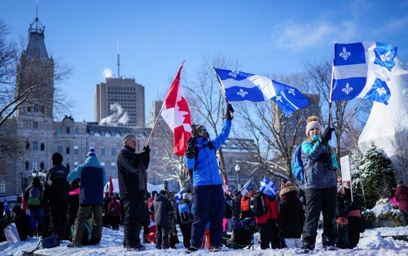 © Reuters. People wave flags near the National Assembly of Quebec, as truckers and their supporters protest against the coronavirus disease (COVID-19) vaccine mandates, in Quebec City, Canada February 5, 2022. REUTERS/Mathieu Belanger