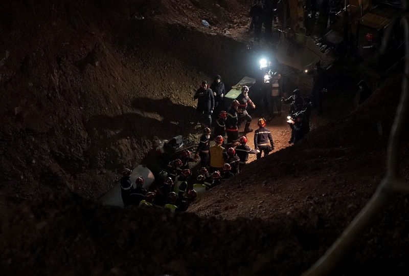 &copy; Reuters. عمال انقاذ يحملون الطفل ريان (5 سنوات) بعد انتشاله من بئر، سقط فيه بالتلال القريبة من مدينة شفشاون شمال المغرب، ويتوجهون لعربة اسعاف يوم السب