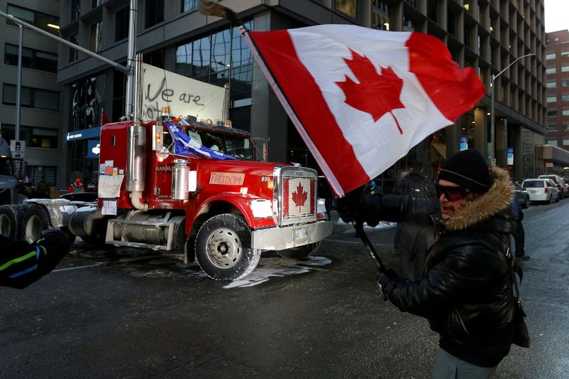 © Reuters. A person waves a Canadian flag in front of a truck, as truckers and supporters continue to protest coronavirus disease (COVID-19) vaccine mandates, in Ottawa, Ontario, Canada, February 5, 2022. REUTERS/Lars Hagberg