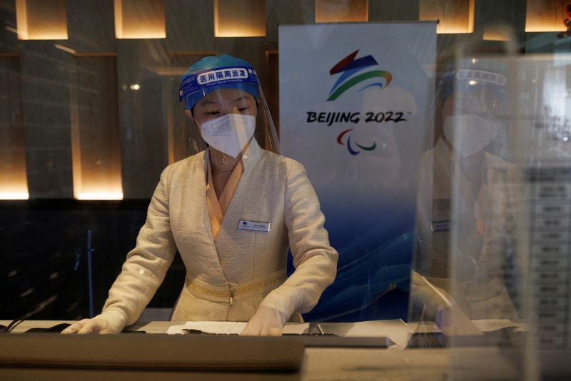 &copy; Reuters. FILE PHOTO: A front desk staff member wearing a mask and a shield as protection against the coronavirus disease (COVID-19) checks in a guest at a hotel inside the closed loop at the Beijing 2022 Winter Olympics in Beijing, China, February 1, 2022.   REUTE