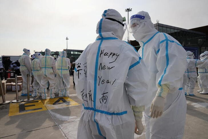 &copy; Reuters. Imagen de archivo de un trabajador sanitario con un equipo protector con el mensaje "Feliz Año Nuevo" en la espalda mientras habla con un colega en el Aeropuerto Internacional de Pekín, China. 31 enero 2022. REUTERS/Kim Hong-Ji