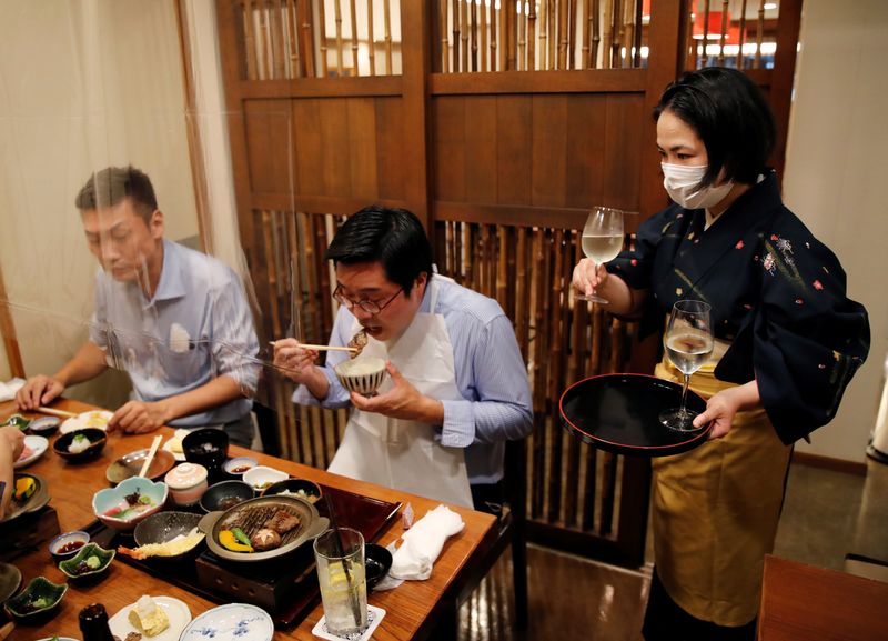 &copy; Reuters. FILE PHOTO: A waitress serves Japanese sake to customers during dinner at Japanese restaurant Kazu, on the first day after Japan lifted the state of emergency imposed due to the coronavirus disease (COVID-19) outbreak, in Tokyo, Japan, October 1, 2021. RE