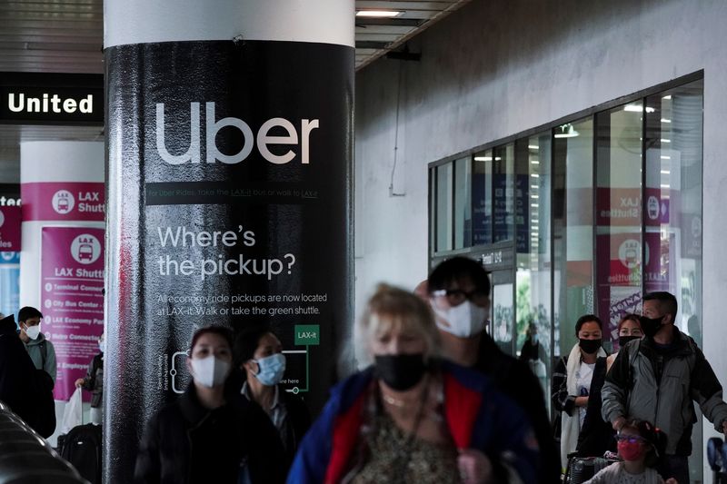 &copy; Reuters. FILE PHOTO: An Uber advertisement is seen behind travelers exiting the baggage claim area at the United Airlines terminal at Los Angeles International Airport (LAX) during the holiday season as the coronavirus disease (COVID-19) Omicron variant threatens 