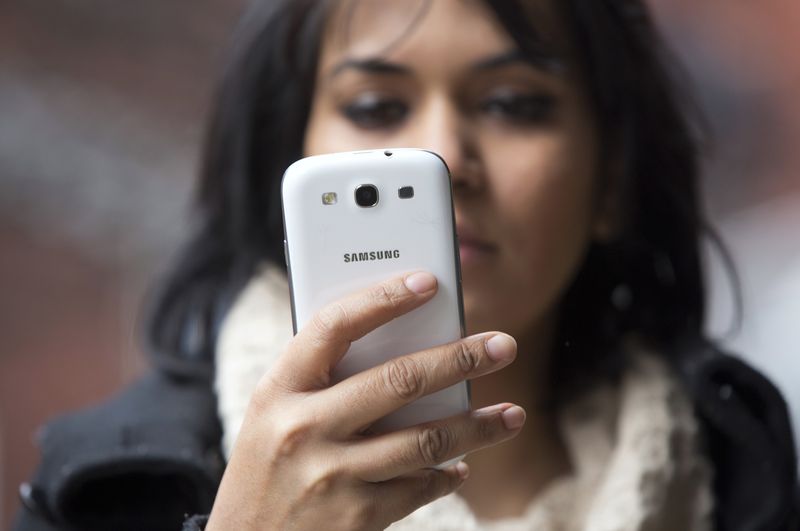 &copy; Reuters. FILE PHOTO: A woman uses a mobile phone in north London February 20, 2013. REUTERS/Neil Hall 