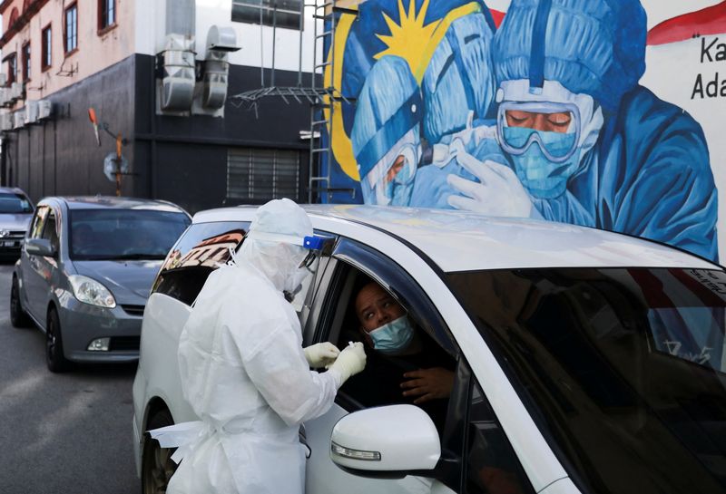 &copy; Reuters. A medical worker conducts nasal swab tests on people at a drive-in coronavirus disease (COVID-19) testing site, as the Omicron variant of the virus spreads and becomes the dominant variant in Shah Alam, Malaysia, February 8, 2022. REUTERS/Hasnoor Hussain