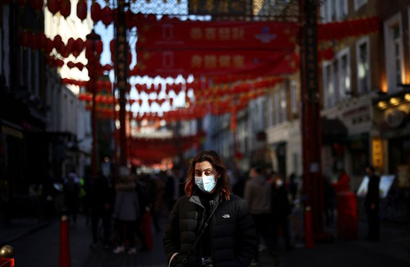 &copy; Reuters. A person wearing a protective face mask as protection against coronavirus disease (COVID-19) walks through Chinatown on the first day of the Lunar New Year in London, Britain, February 1, 2022. REUTERS/Henry Nicholls