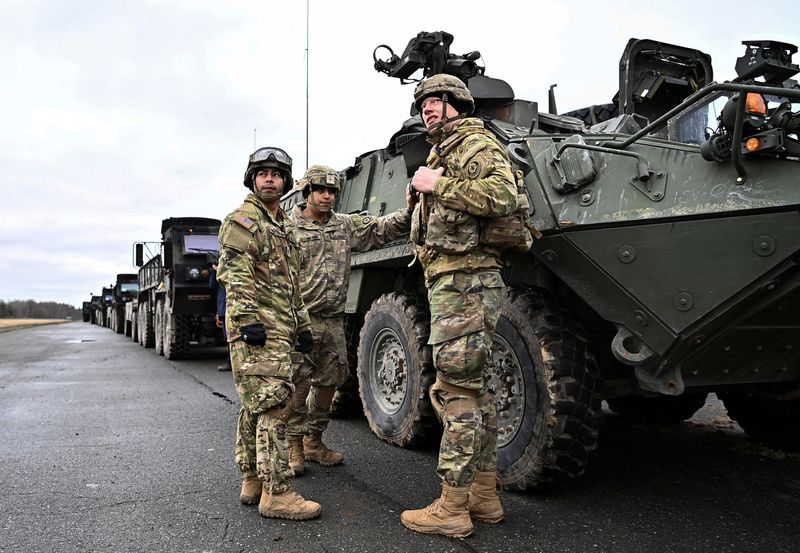 © Reuters. Soldiers of the U.S. 2nd Cavalry Regiment stand next to a combat vehicle as they prepare their gear for deployment to Romania at Rose Barracks in Vilseck, Germany, February 9, 2022.  REUTERS/Lukas Barth 