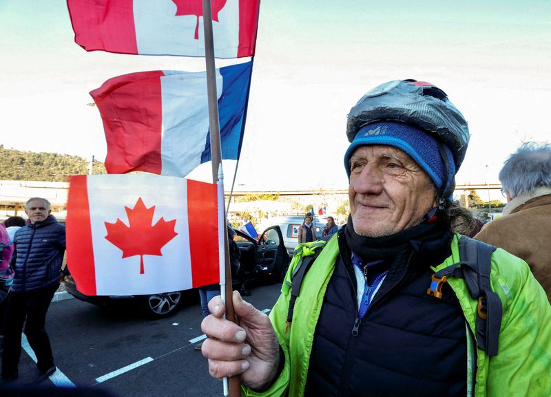 © Reuters. A French activist holds a Canadian flag before the start of their 