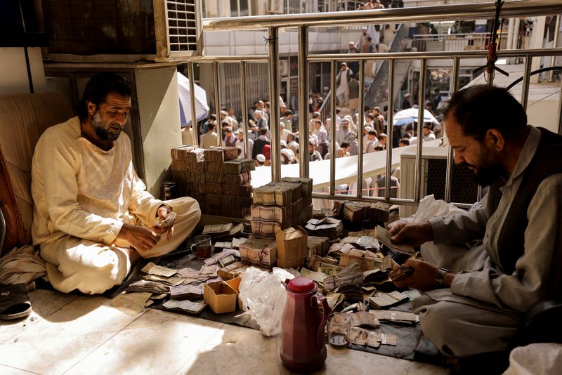 &copy; Reuters. FILE PHOTO: Afghan currency exchange workers count money at a market in Kabul, Afghanistan October 7, 2021. REUTERS/Jorge Silva/File Photo