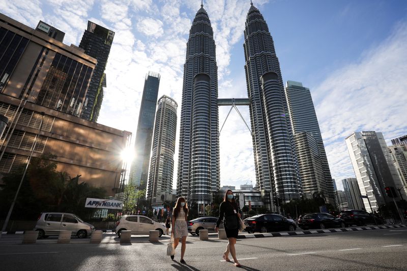 &copy; Reuters. FILE PHOTO: People wearing protective masks cross a street in front of Petronas Twin Towers, amid the coronavirus disease (COVID-19) outbreak in Kuala Lumpur, Malaysia January 11, 2021. REUTERS/Lim Huey Teng