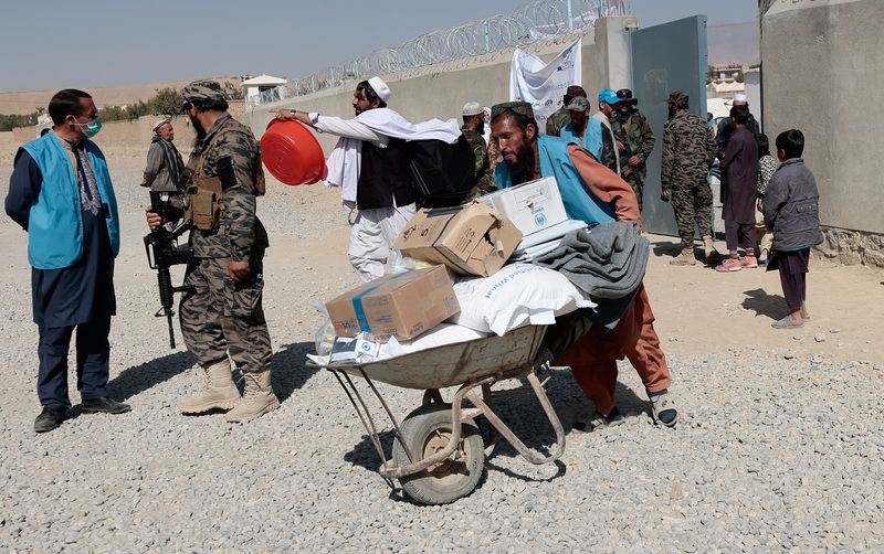 &copy; Reuters. FILE PHOTO: An UNHCR worker pushes a wheelbarrow  loaded with aid supplies for a displaced Afghan family outside the distribution center as a Taliban fighter secures the area on the outskirts of Kabul, Afghanistan October 28, 2021. REUTERS/Zohra Bensemra