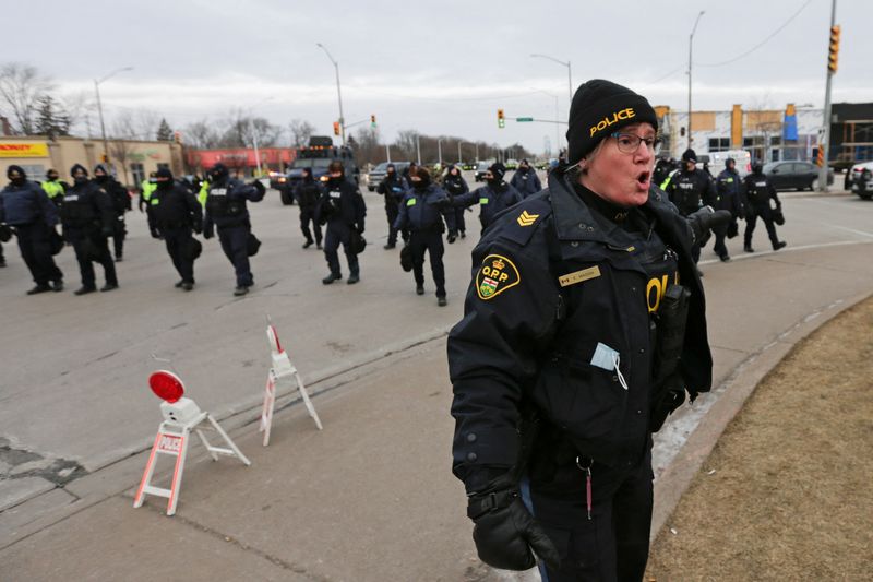 © Reuters. A police officer reacts on the road leading to the Ambassador Bridge, which connects Detroit and Windsor, after police cleared demonstrators, during a protest against coronavirus disease (COVID-19) vaccine mandates, in Windsor, Ontario, Canada February 13, 2022. REUTERS/Carlos Osorio