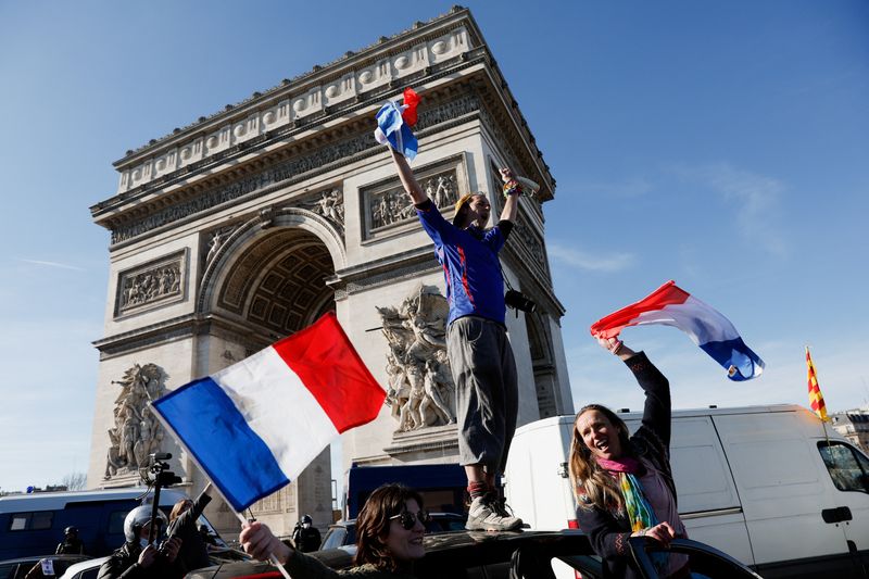 © Reuters. 　２月１２日、フランスのパリで、新型コロナウイルス対策の規制に抗議する人達が車列を作って市の中心部に集まり、凱旋門周辺やシャンゼリゼ通りで交通渋滞を引き起こした。写真は車の上で抗議する人。パリで１２日撮影（２０２２年　ロイター／Benoit Tessier）
