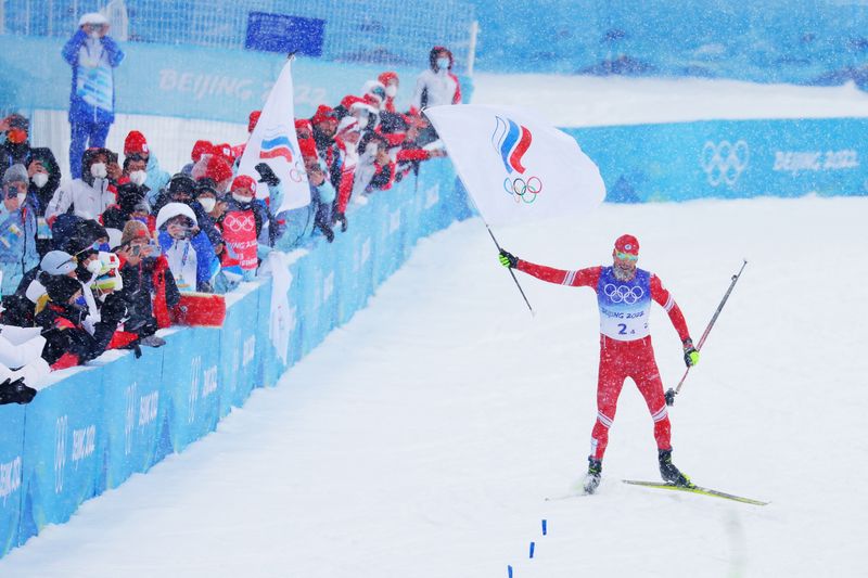 &copy; Reuters. 2022 Beijing Olympics - Cross-Country Skiing - Men's 4 x 10km Relay - National Cross-Country Centre, Zhangjiakou, China - February 13, 2022. Sergey Ustiugov of the Russian Olympic Committee waves his national flag as he crosses the finish line. REUTERS/Ma