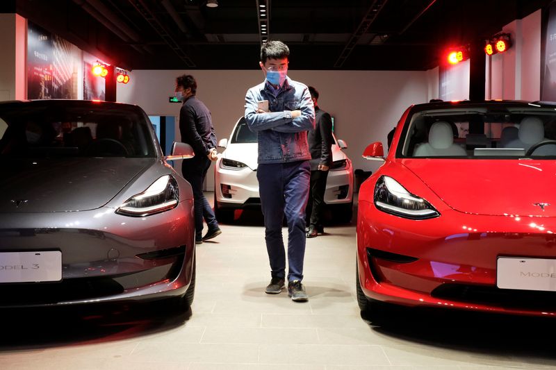 &copy; Reuters. A man wearing a face mask following the coronavirus disease (COVID-19) outbreak walks by Tesla Model 3 sedans and Tesla Model X sport utility vehicle at a new Tesla showroom in Shanghai, China May 8, 2020. Picture taken May 8, 2020. REUTERS/Yilei Sun
