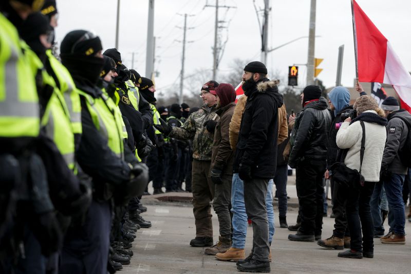 &copy; Reuters. FILE PHOTO: Protesters interact with police officers, who stand guard on a street after Windsor Police said that they are starting to enforce a court order to clear truckers and supporters who have been protesting against coronavirus disease (COVID-19) va