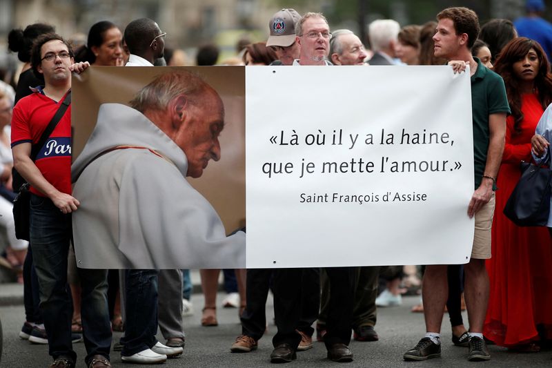 &copy; Reuters. فرنسيون يحملون لافتة عليها صورة الأب جاك هامل وكتب عليها "أينما وجدت الكراهية دعوني أنثر الحب" في تجمع لذكراه عند كاتدراية نوتردام في باريس 