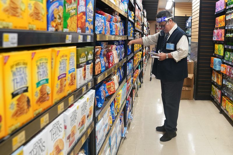 &copy; Reuters. FILE PHOTO  - A worker with a face shield checks products on the shelf of a grocery store in the Manhattan borough of New York City, New York, U.S., August 7, 2020. REUTERS/Carlo Allegri