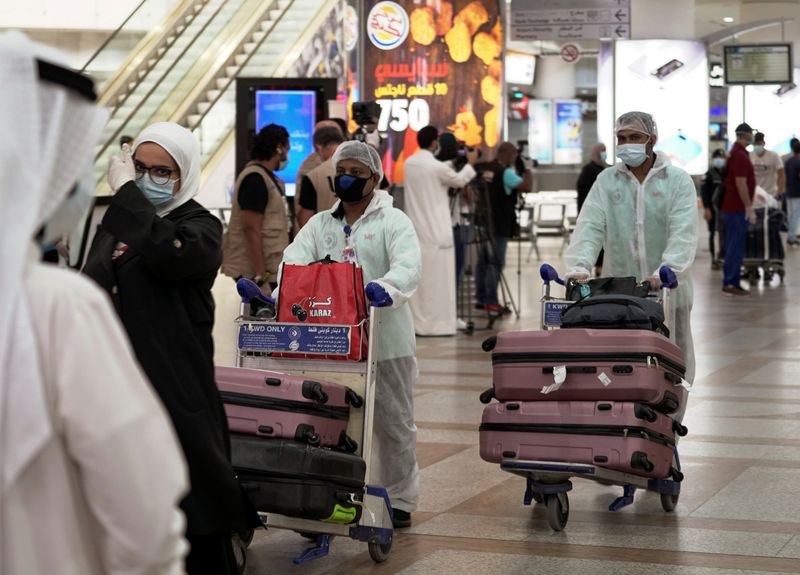 © Reuters. FOTO DE ARCHIVO: Varios ciudadanos kuwaitíes procedentes de Amán, capital de Jordania, con mascarillas y ropa de protección a su llegada al aeropuerto de Kuwait, el 21 de abril de 2021. REUTERS/Stephanie McGehee
