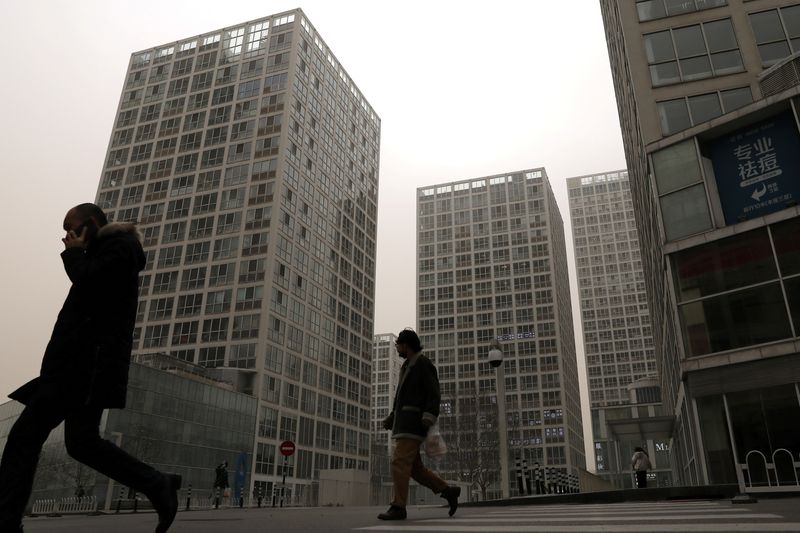 &copy; Reuters. FILE PHOTO: People walk past an office and commercial complex in Beijing's Central Business District (CBD), China March 15, 2021. REUTERS/Tingshu Wang