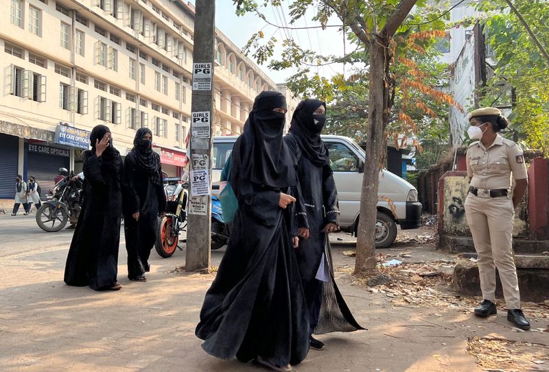 &copy; Reuters. Hijab wearing schoolgirls arrive to attend their classes as a policewoman stands guard outside a government girls school after the recent hijab ban, in Udupi town in the southern state of Karnataka, India, February 16, 2022. REUTERS/Sunil Kataria