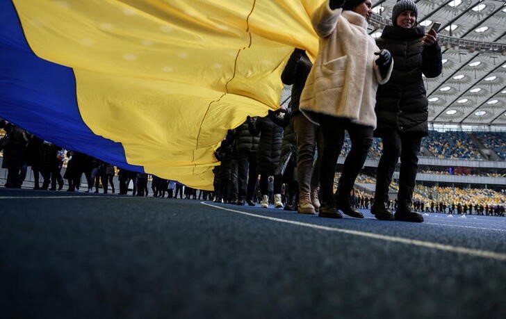 &copy; Reuters. Residentes portan una bandera nacional gigante en el estadio olímpico de Kiev para conmemorar el día de la unidad nacional. Febrero 16, 2022. REUTERS/Umit Bektas