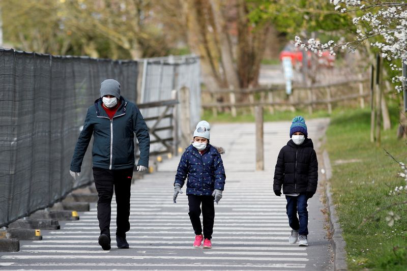 &copy; Reuters.  A man and children wearing protective face masks walk near a Chessington World of Adventures car park, which has been turned into a testing facility as the spread of the coronavirus disease (COVID-19) continues, Chessington, Britain, March 28, 2020. REUT