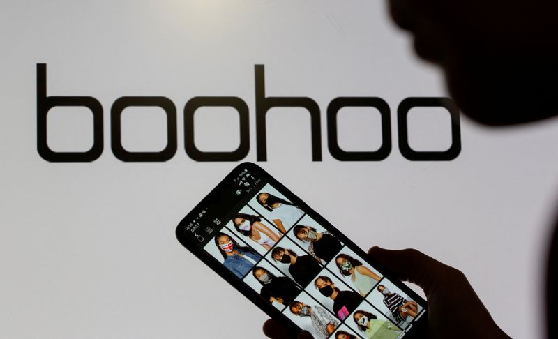 &copy; Reuters. Mulher segura celular mostrando o aplicativo da Boohoo em frente ao logo da Boohoo em foto de ilustração
30/09/2020 REUTERS/Dado Ruvic