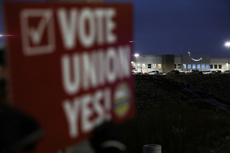 © Reuters. FILE PHOTO: A person affiliated with RWDSU (Retail, Wholesale and Department Store Union) holds a sign supporting unionization in front of an Amazon facility on the first day of the unionization vote in Bessemer,  Alabama, U.S., February 4, 2022. REUTERS/Dustin Chambers