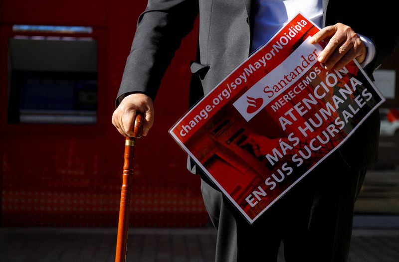 &copy; Reuters. Retired Carlos San Juan, creator of the "SoyMayorNoIdiota" ("I'm old, not an idiot") campaign, holds a sign reading "We deserve more attention in your branches", in front of a bank branch in Madrid, Spain, February 8, 2022.  REUTERS/Borja Suarez.