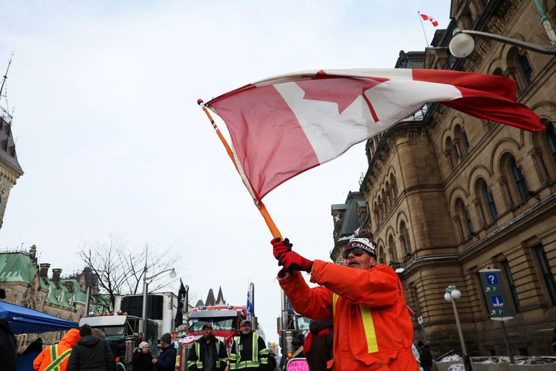 &copy; Reuters. A man waves the flag of Canada around parked trucks, as protests against coronavirus disease (COVID-19) vaccine mandates continue, in Ottawa, Ontario, Canada, February 16, 2022. REUTERS/Shannon Stapleton