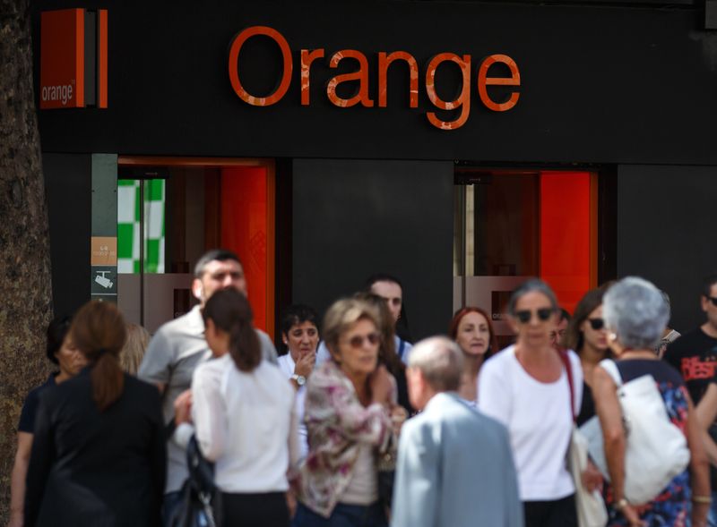 &copy; Reuters. Des personnes traversent une rue devant une boutique Orange à Madrid. Orange est prêt à participer à toute opération susceptible de réduire le nombre d'opérateurs télécoms en Espagne, son deuxième marché après la France, a déclaré jeudi Sté