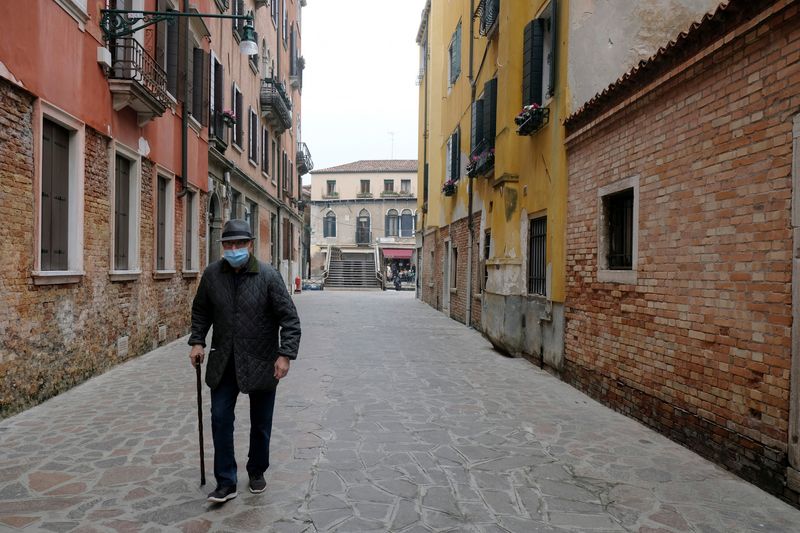 © Reuters. FILE PHOTO: An elderly man with a protective mask walks in Venice, on the fourth day of an unprecedented lockdown across all country, imposed to slow the outbreak of coronavirus, Italy March 13, 2020. REUTERS/Manuel Silvestri/File Photo