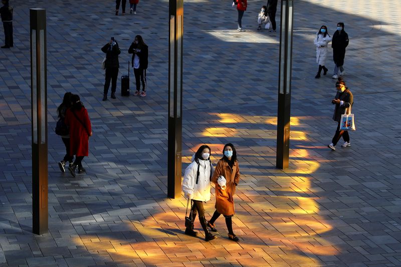 © Reuters. People wearing masks to prevent the spread of the coronavirus disease (COVID-19) walk at a shopping complex in Beijing, China December 1, 2021. REUTERS/Tingshu Wang     