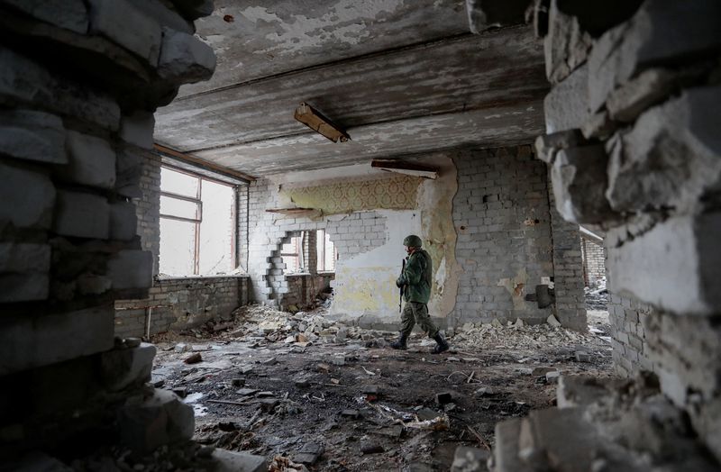 © Reuters. A militant of the self-proclaimed Luhansk People's Republic patrols the damaged building of a local school located near the line of separation from the Ukrainian armed forces in the settlement of Molodizhne (Molodezhnoye) in the Luhansk region, Ukraine February 17, 2022. REUTERS/Alexander Ermochenko