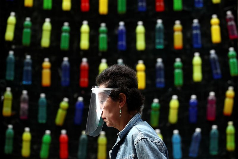 &copy; Reuters. Una mujer con una protección facial pasa por delante de una pared decorada con botellas de colores en medio del brote de la enfermedad del coronavirus (COVID-19) en Madrid, España, 7 de mayo de 2020. REUTERS/Sergio Pérez