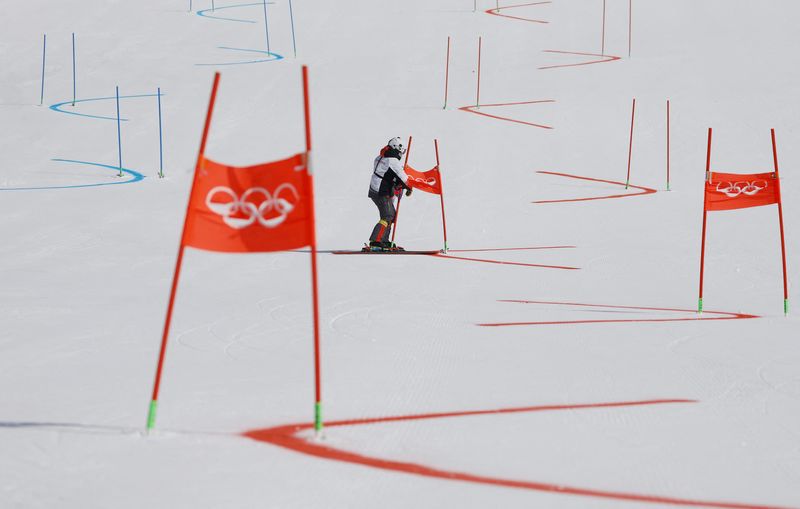 &copy; Reuters. 2022 Beijing Olympics - Alpine Skiing - Mixed Team Parallel 1/8 Finals - National Alpine Skiing Centre, Yanqing district, Beijing, China - February 19, 2022. An Olympic staff member on the course removes gate flags after the event was postponed due to wea