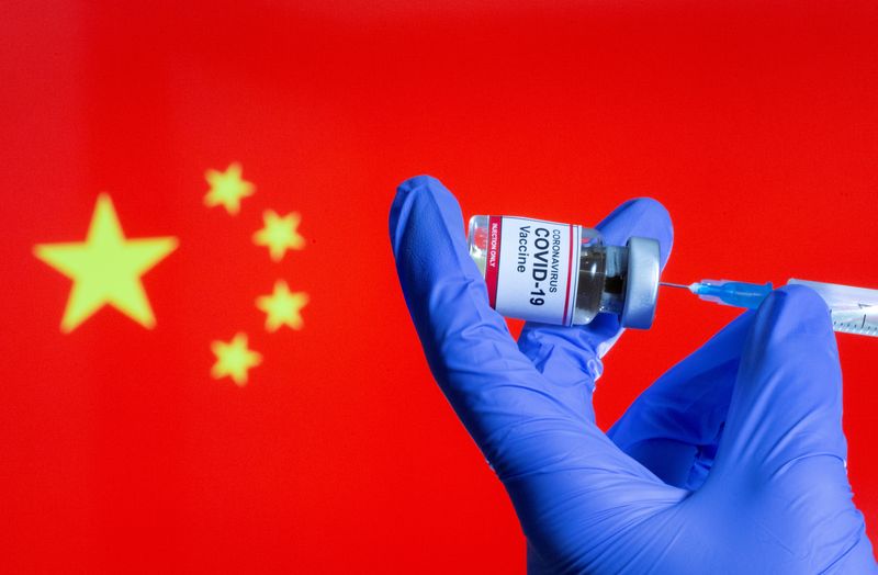 &copy; Reuters. FILE PHOTO: A woman holds a small bottle labeled with a "Coronavirus COVID-19 Vaccine" sticker and a medical syringe in front of displayed China flag in this illustration taken, October 30, 2020. REUTERS/Dado Ruvic/File Photo