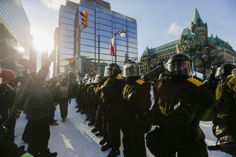 © Reuters. Canadian police officers stand guard as they work to restore normality to the capital while trucks and demonstrators continue to occupy the downtown core for more than three weeks to protest against coronavirus disease (COVID-19) pandemic restrictions in Ottawa, Ontario, Canada, February 19, 2022.  REUTERS/Carlos Osorio