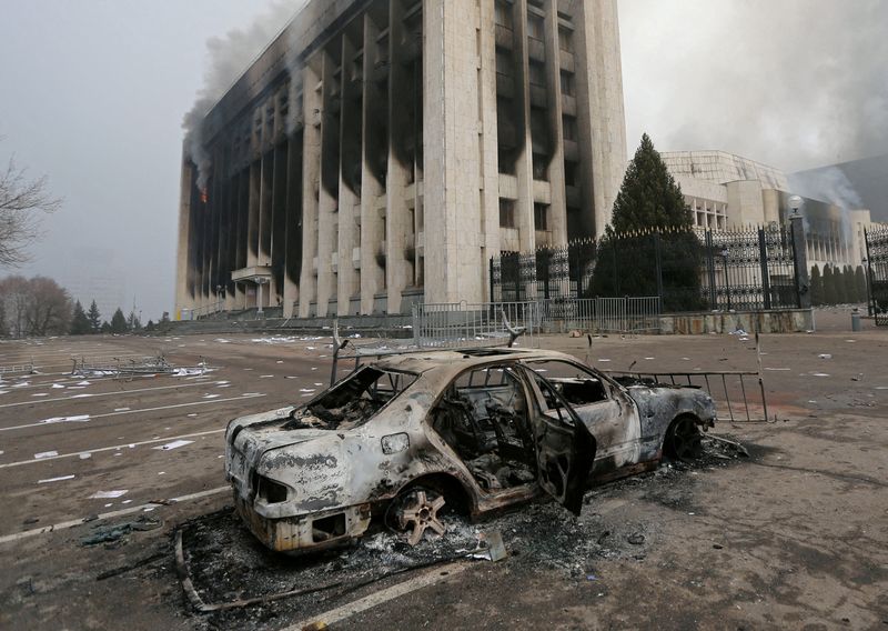 &copy; Reuters. سيارة محترقة أمام مبنى مكتب العمدة الذي اشتعلت به النيران خلال الاحتجاجات في ألما اتة  يوم السادس من يناير كانون الثاني 2022. تصوير: بافيل ميخي