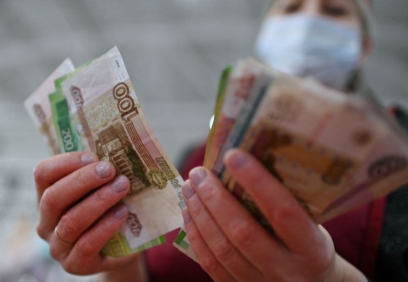© Reuters. FILE PHOTO: A vendor counts Russian rouble banknotes at a market in Omsk, Russia February 18, 2022. REUTERS/Alexey Malgavko