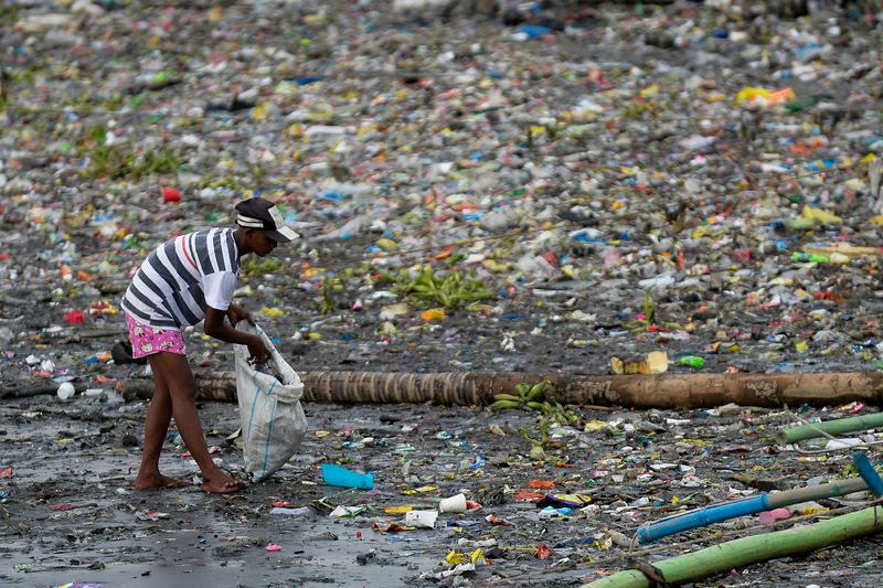 &copy; Reuters. FILE PHOTO: A woman picks up plastic cups along the riverbank of Pasig river, in Manila, Philippines, June 10, 2021. REUTERS/Lisa Marie David
