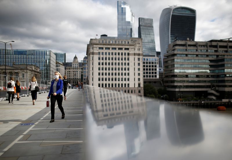 © Reuters. The financial district can be seen as a woman wearing a protective face mask walks over London Bridge, amid the coronavirus disease (COVID-19) outbreak, in London, Britain, August 26, 2020. REUTERS/Henry Nicholls