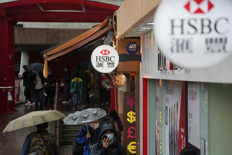 © Reuters. Pedestrians wearing face masks following the coronavirus disease (COVID-19) outbreak, walk past a HSBC bank branch in Hong Kong, China February 22, 2022. REUTERS/Lam Yik