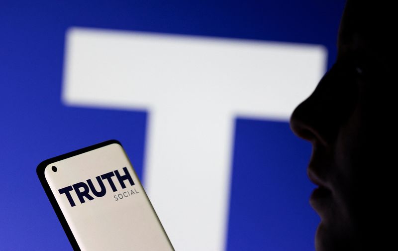 &copy; Reuters. The Truth social network logo is seen displayed behind a woman holding a smartphone in this picture illustration taken February 21, 2022. REUTERS/Dado Ruvic/Illustration