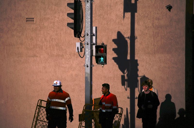 &copy; Reuters. FILE PHOTO: Workers carry barriers as they wait to cross a street at a set of traffic lights with pedestrians at sunset in central Newcastle, located north of Sydney, Australia, August 13, 2018. REUTERS/David Gray