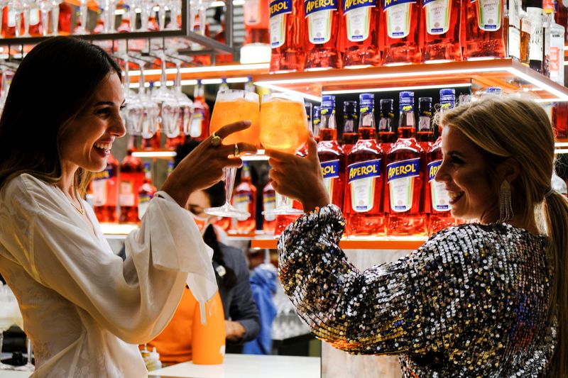 &copy; Reuters. FILE PHOTO: Women holding drinks attend a Campari inauguration of a new brand house for Aperol, its best-selling beverage, in Venice Italy, August 30, 2021. REUTERS/Manuel Silvestri