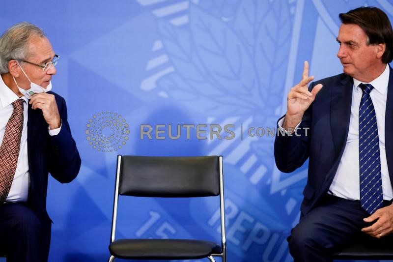 &copy; Reuters. O presidente Jair Bolsonaro fala com o ministro da Economia, Paulo Guedes, durante cerimônia para o lançamento da carteira de identidade nacional, no Palácio do Planalto, Brasília, 23 de fevereiro de 2022. REUTERS/Ueslei Marcelino